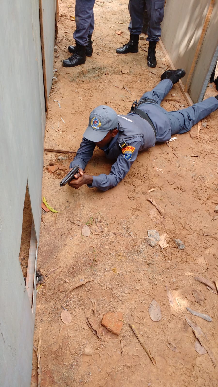 Registro da época na PMMA durante treinamento em campo, com policial uniformizado em posição deitada e colegas ao fundo